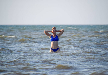 一个穿着蓝色泳衣的女孩沐浴在海里。海滨度假酒店