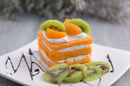 橙色和猕猴桃蛋糕在木背景