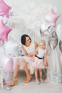 快乐的母亲和女儿穿着漂亮的衣服, 用气球庆祝节日。色调