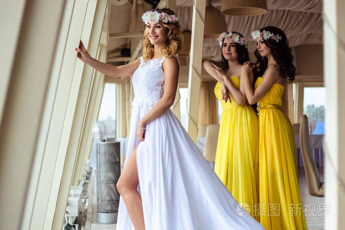美丽的新娘和两个伴娘穿着黄色类似一起在海上餐厅