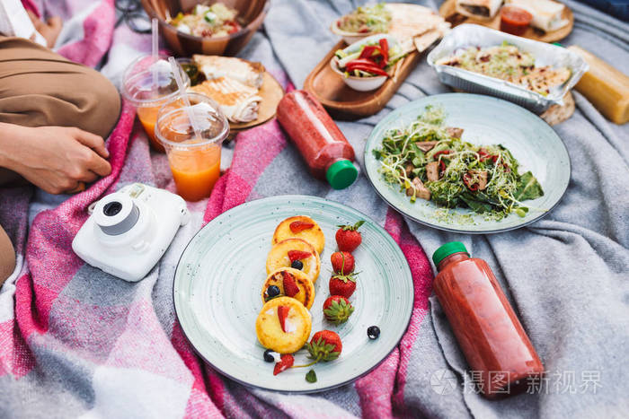 关闭在公园毯子上美丽的野餐食品和饮料的照片