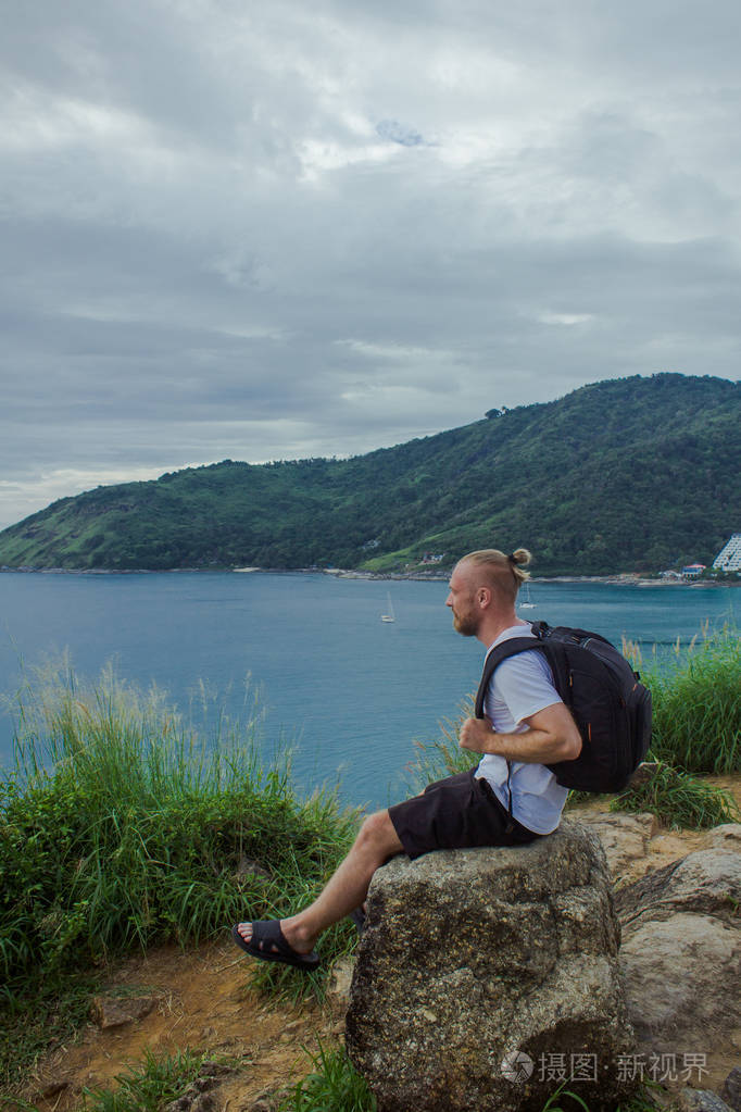 坐在石头上的背包客.一个人坐在侧面图