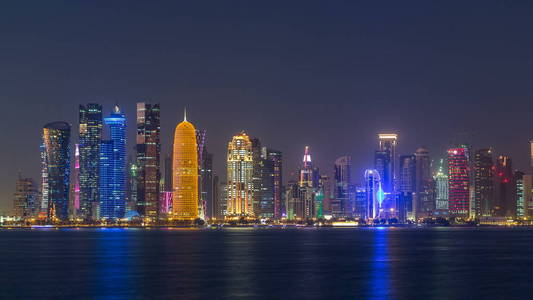 多哈市中心天际线天到夜过渡 timelapse, 卡塔尔, 中东。在海湾的水中反映出一个西海湾的照明摩天大楼