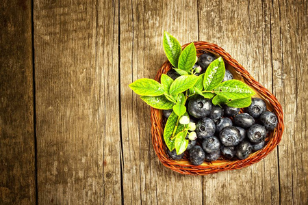 湿蓝莓在一个小柳条篮子。新采摘的森林水果在一张木桌上。销售蓝莓。健康夏日茶点