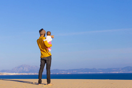 年轻的爸爸带着小女儿走在海边, 快乐的家庭放松