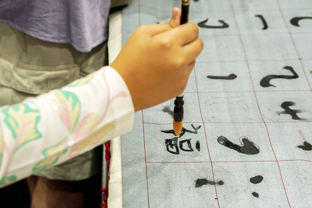 手持中国画笔的人的特写手和展示中国文字的织物