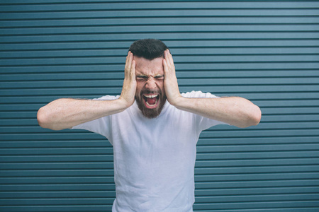 照片中有压力的年轻人感到可怕的头痛, 沮丧和沮丧, 握紧的牙齿在疼痛