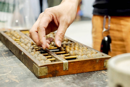 古黑木桌上中国古代算盘的人的特写手和示范用照片