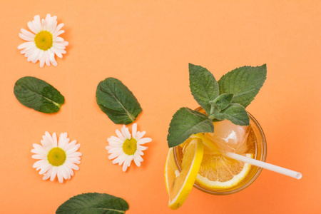 菊花桃高杯清凉的夏日柠檬水, 有冰,柠檬片,薄荷叶和菊花色的背景.