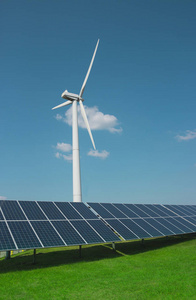 风力发电机的电力从三叶片和太阳能电池板的光电的背景下的云和蓝色的天空绿草