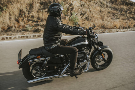 骑美式经典摩托车的经典摩托车骑手侧面视图照片