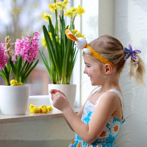 小女孩装饰的窗口与春天的花朵和复活节彩蛋。照看植物的孩子。幼儿照顾风信子和水仙花。复活节家庭内饰和装饰