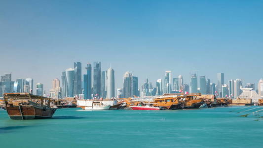在卡塔尔的多哈, timelapse 的旧的三角帆船海港的全景, 与西海湾的天际线背景。现代摩天大楼在背景和老小船在前景上