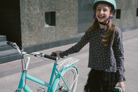 十几岁的女孩用一辆自行车在一条街上休息