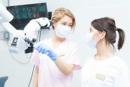 专业牙科双目显微镜, 两个女牙医看着对方, 在医疗口罩