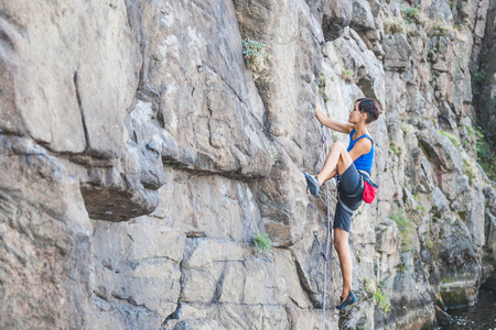 一个女人爬上岩石。自然地形的训练。极限运动。登山者在自然的浮雕上训练
