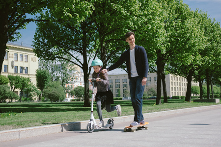 爸爸和女儿一起骑滑板车和滑板