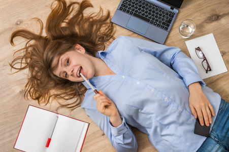 微笑的女人躺在回与手提电脑和智能手机