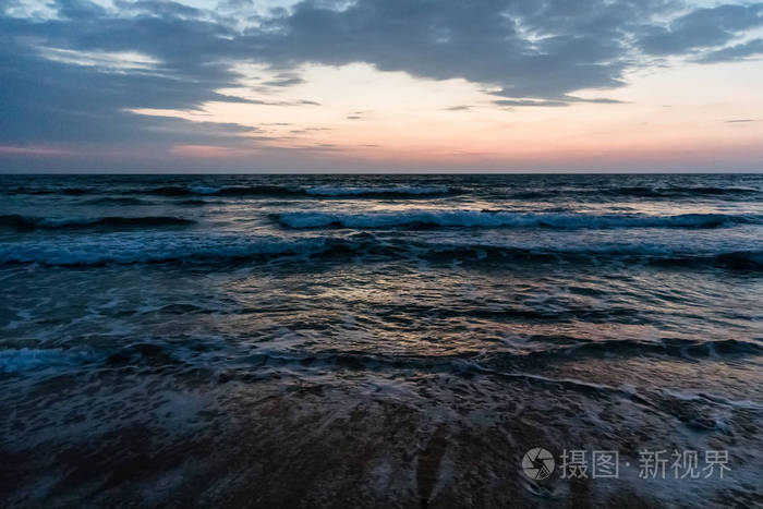 在美国佛罗里达州新的麦地那海滩的雨云中日出 海浪拍打着海滩上沙子上的海沫 在多云的天空中 清晨日出的戏剧性景色 照片 正版商用图片0rbzr6 摄图新视界