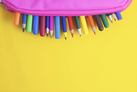 彩色铅笔学校用品粉红色的情况下黄色背景。回到学校
