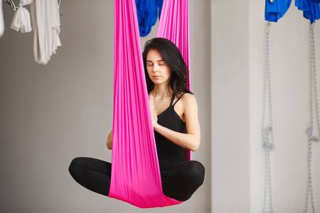 空中的丝绸空中反重力瑜伽女孩姿势丝绸的吊床上照片