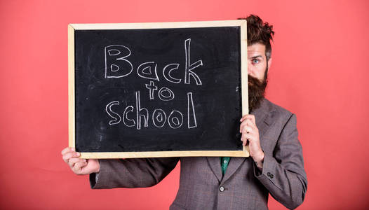 老师或校长欢迎回到学校。你准备好学习了吗老师躲在黑板后面。准备开学一年。老师从黑板上偷看红色背景
