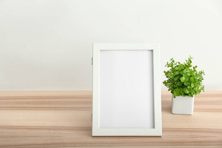 白色墙壁上的空白相框和盆栽