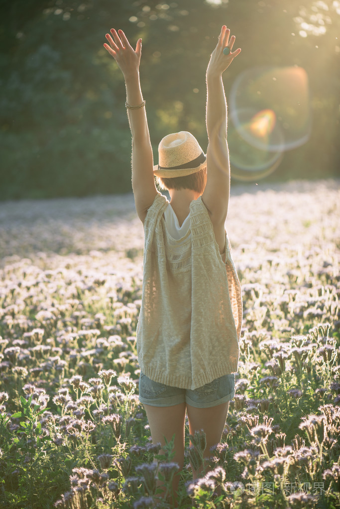 美丽的女人用享受和平,宁静自然的伸开双臂拥抱金色阳光落日的余晖