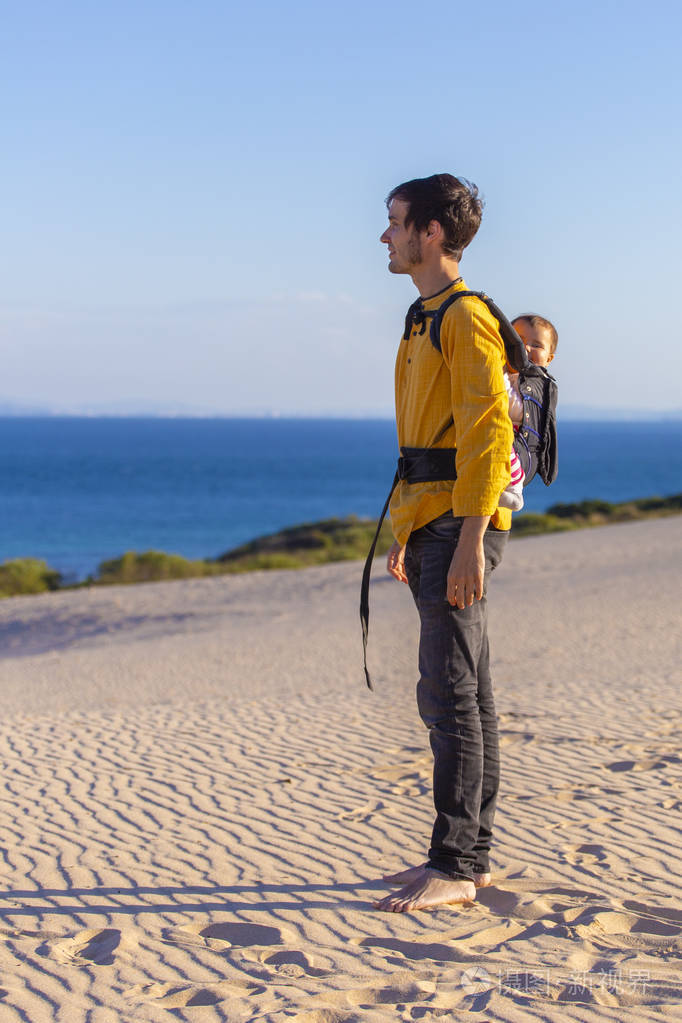 年轻的爸爸背着小女儿在背包里散步