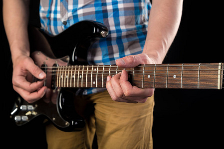 音乐和艺术。电吉他在手中的吉他手，在一个黑色的孤立的背景。弹吉他。水平框架