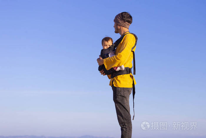 年轻的爸爸背着小女儿在背包里散步