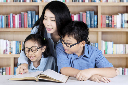 漂亮的老师教她的学生在图书馆照片