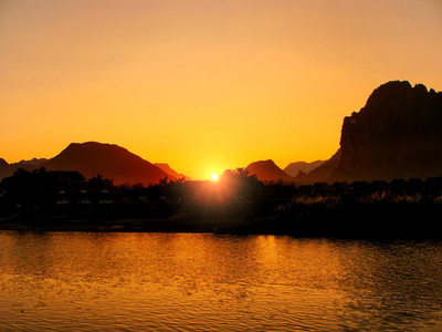 夕阳在南松河与老挝万荣剪影的岩层。万荣是石灰岩岩溶景观冒险旅游热门目的地