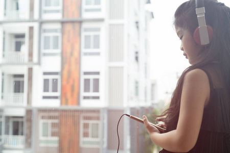 漂亮的亚洲女孩拿着智能手机，听着音乐才子