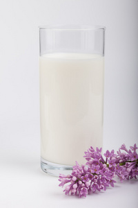 杯牛奶和淡紫色白色背景上