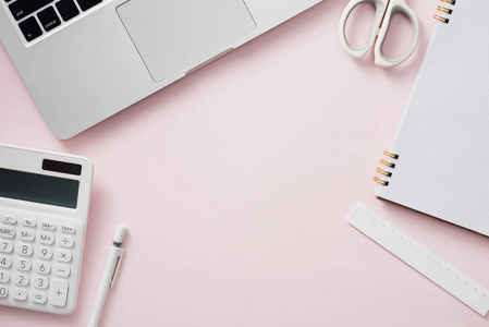 带笔记本电脑的空白笔记本和粉红色办公桌上的办公用品