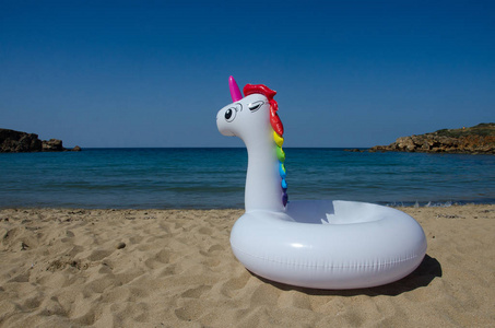充气独角兽漂浮在海边的沙子上。暑假, 海滩度假。梦幻游泳圈。Copyplace, 地方为文本