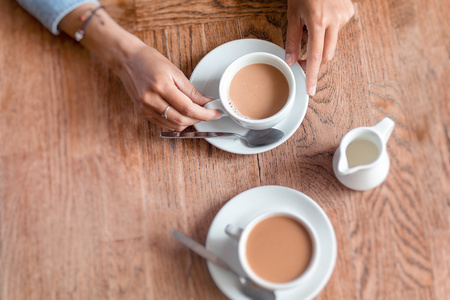 两杯咖啡和女人手在咖啡厅的木桌上