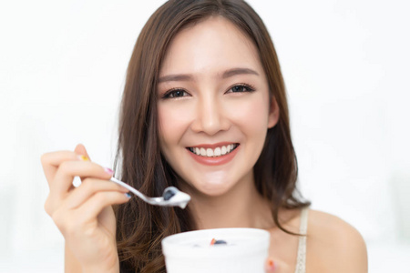 健康的生活方式。微笑着快乐的年轻亚洲妇女在家里吃水果和酸奶, 看着相机。减肥食品的概念。高分辨率