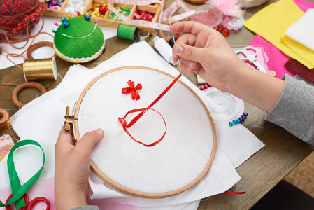 绣箍 手特写和白色的纺织品，红色缎带上的男孩学会了缝纫 就业培训 手工制作和工艺品概念
