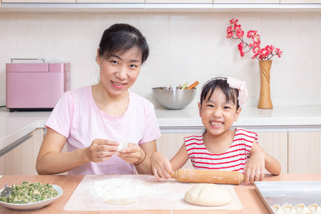 亚洲华人妈妈和女儿在家厨房做饺子