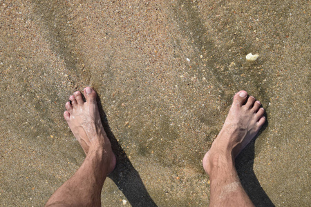 腿上的人在海上的沙子附近的海浪。漫步在沙滩上