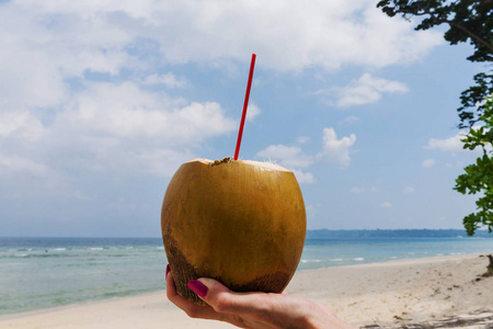 新鲜椰子鸡尾酒手上的绿松石海背景, 旅行卡, 与弯曲的地平线线.