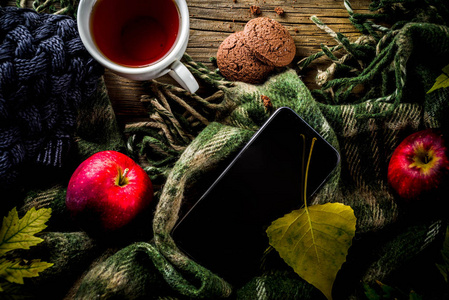 秋季主题背景, 老式木制木板板, 与格子, 毛衣和秋季黄叶, 茶杯, 苹果和巧克力曲奇饼干, 与智能手机顶部视图复制空间
