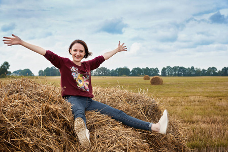 在田野里玩的年轻女孩, 坐在干草堆上