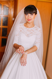 在华丽的白色连衣裙，显示她珍珠手链，一边穿仪式前反叛新娘