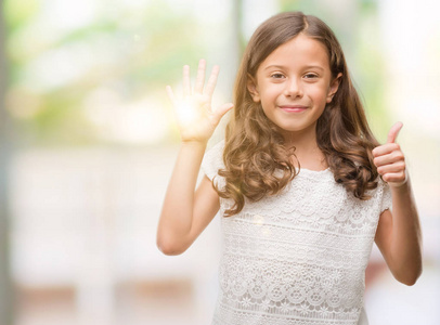 手指六黑发西班牙裔女孩显示和指向手指数六, 而微笑着自信和快乐照片