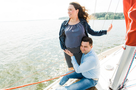 在游艇上和丈夫在一起的怀孕妇女。快乐怀孕的概念。年轻家庭度假