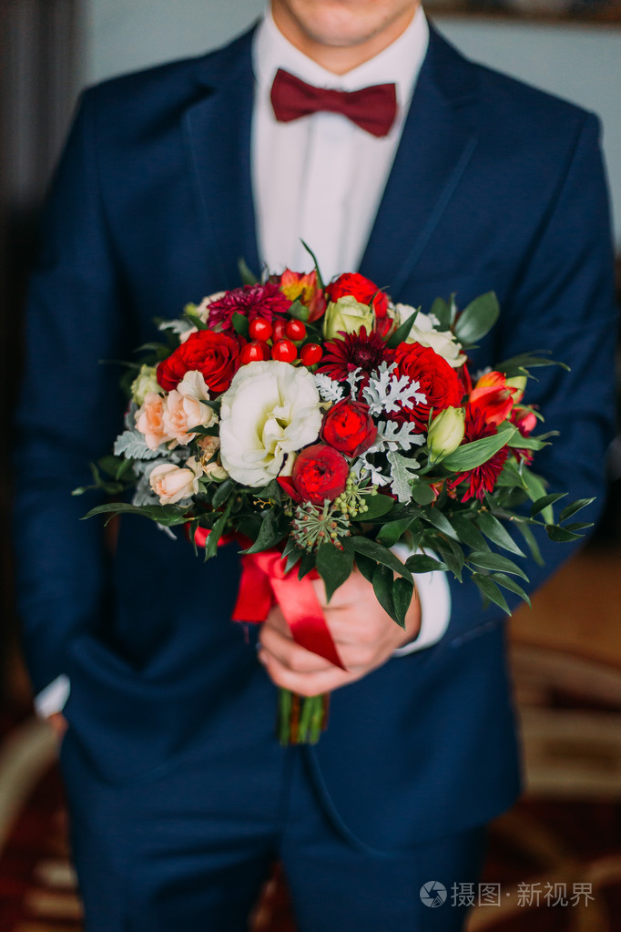 时髦的年轻人抱着红色和白色婚礼花束