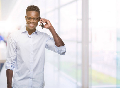 年轻的非洲裔美国人使用智能手机与快乐的脸站在微笑着一个自信的微笑显示牙齿